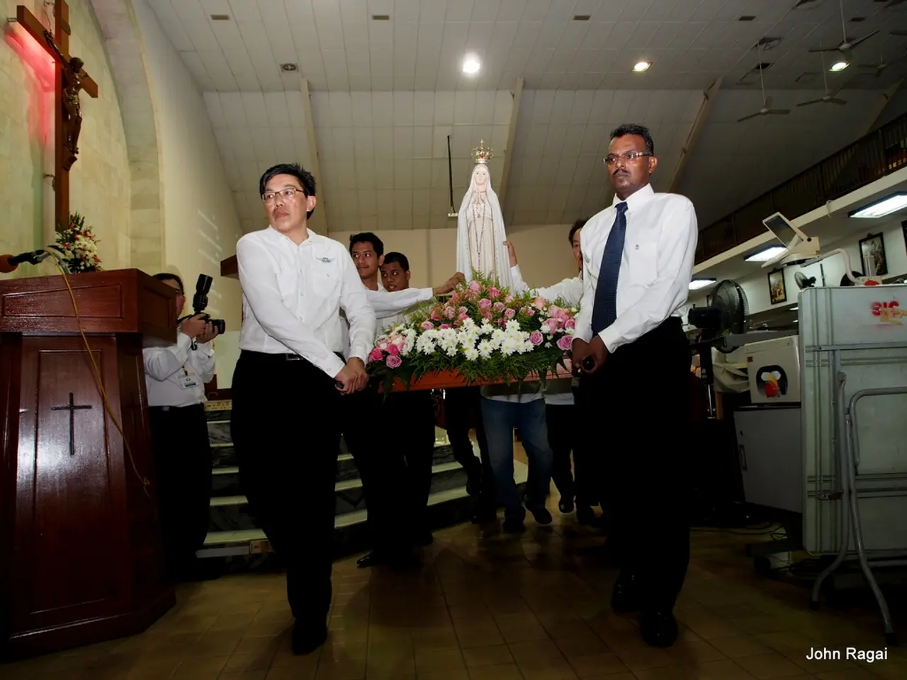 In this image I see few men who are carrying this thing on which there are flowers and I see a...