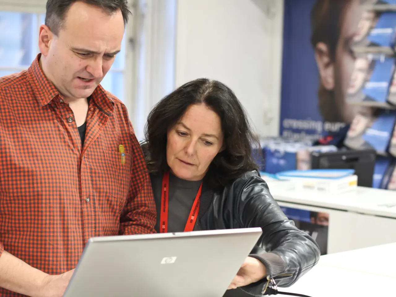 In this image, we can see people using laptop and one of them is wearing an id card. In the...