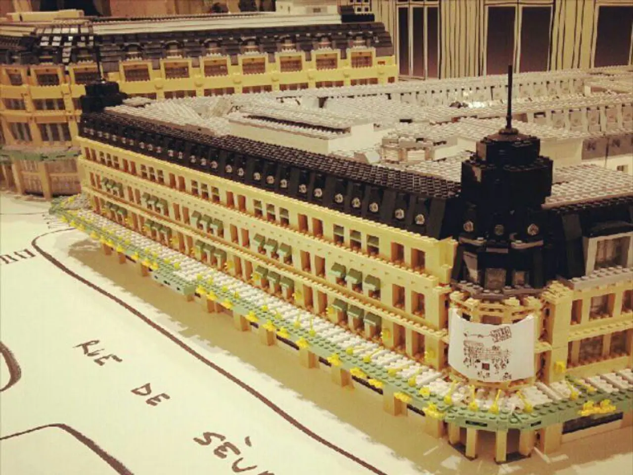 In this image we can see model of buildings. At the bottom of the image, some text is written.