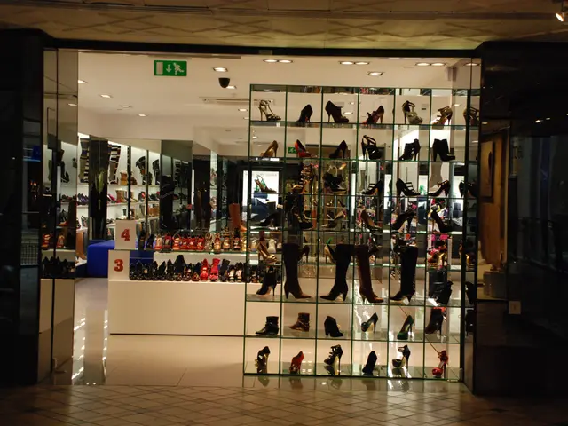 In this picture, we see many shoes are displayed. Behind that, we see a white table on which shoes...