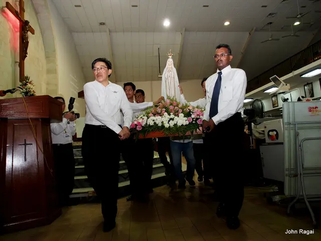 In this image I see few men who are carrying this thing on which there are flowers and I see a...