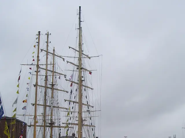 In this image we can see some ships in the water body. We can also see some buildings, a walkway...