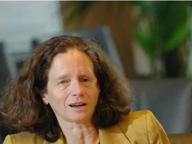 This Image consists of a woman who is sitting in sofa. Table is in front of her on that table there...